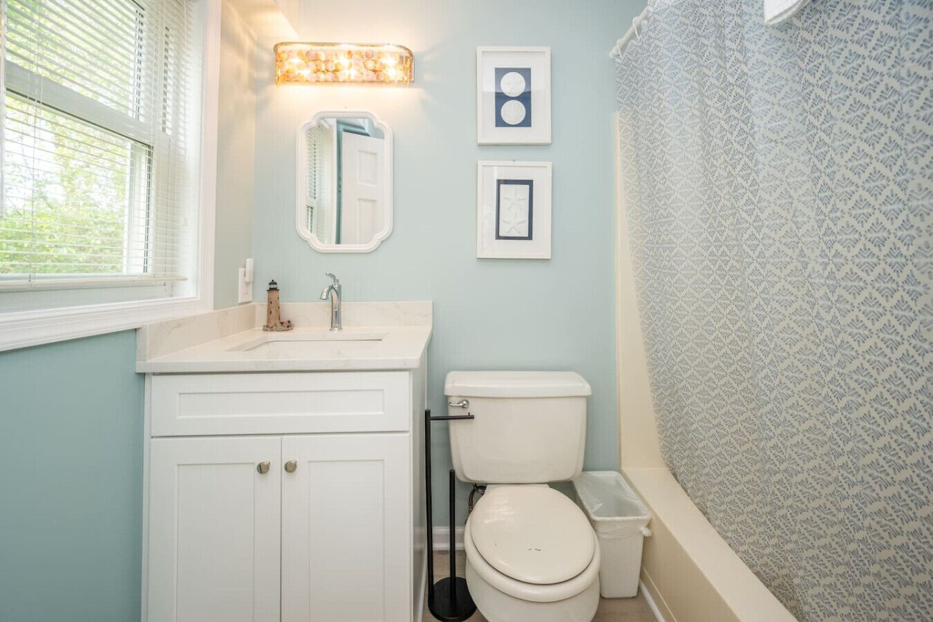 A bathroom with a white sink, a toilet, and a shower curtain with a geometric pattern.