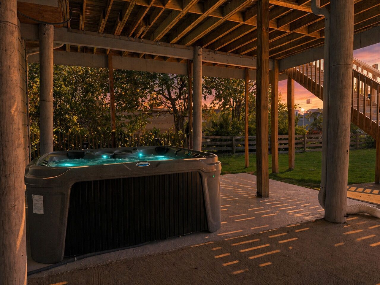 Ett bubbelbad under en träpergola med utsikt över ett bostadsområde.