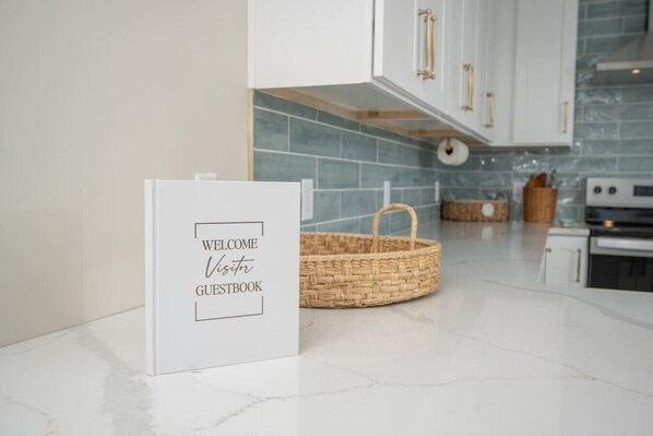 A kitchen with white cabinets, a blue tiled backsplash, and a wicker basket on the counter.