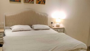 Une chambre à coucher avec un grand lit, une table de chevet et trois œuvres d’art accrochées au mur.