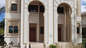 Un bâtiment à la façade symétrique, doté de grandes portes cintrées et d’une entrée centrale.