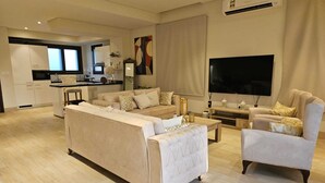 Un salon moderne comprenant un canapé, des fauteuils, une table basse et un téléviseur.