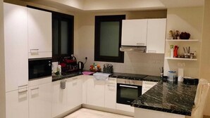 Une cuisine moderne avec des meubles blancs, un plan de travail noir et un four encastré.