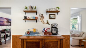 A kitchen with wooden cabinets, a coffee maker, and two shelves with kitchen items.