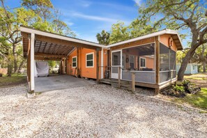 Une maison à deux étages dotée d’un patio couvert, d’une véranda grillagée et d’une allée en gravier.