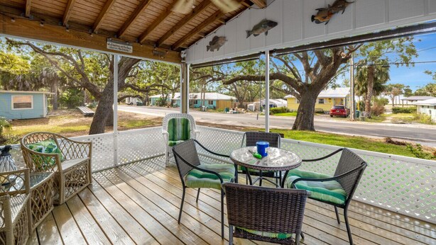 A covered outdoor area with wicker furniture, a table, and a ceiling fan.