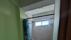 Casa de banho com sanita, chuveiro com cortina e janela que proporciona luz natural.