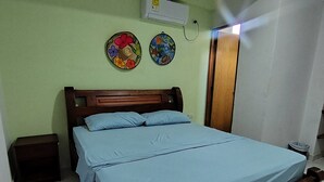 Quarto com cama de madeira, paredes verdes e duas decorações na parede.