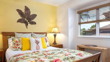 A hotel room with a bed, a nightstand, a lamp, a wall art piece, a window with blinds, and a small table with a magazine.