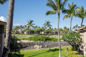 Un resort con varias edificaciones, palmeras y un área ajardinada con césped y arbustos.