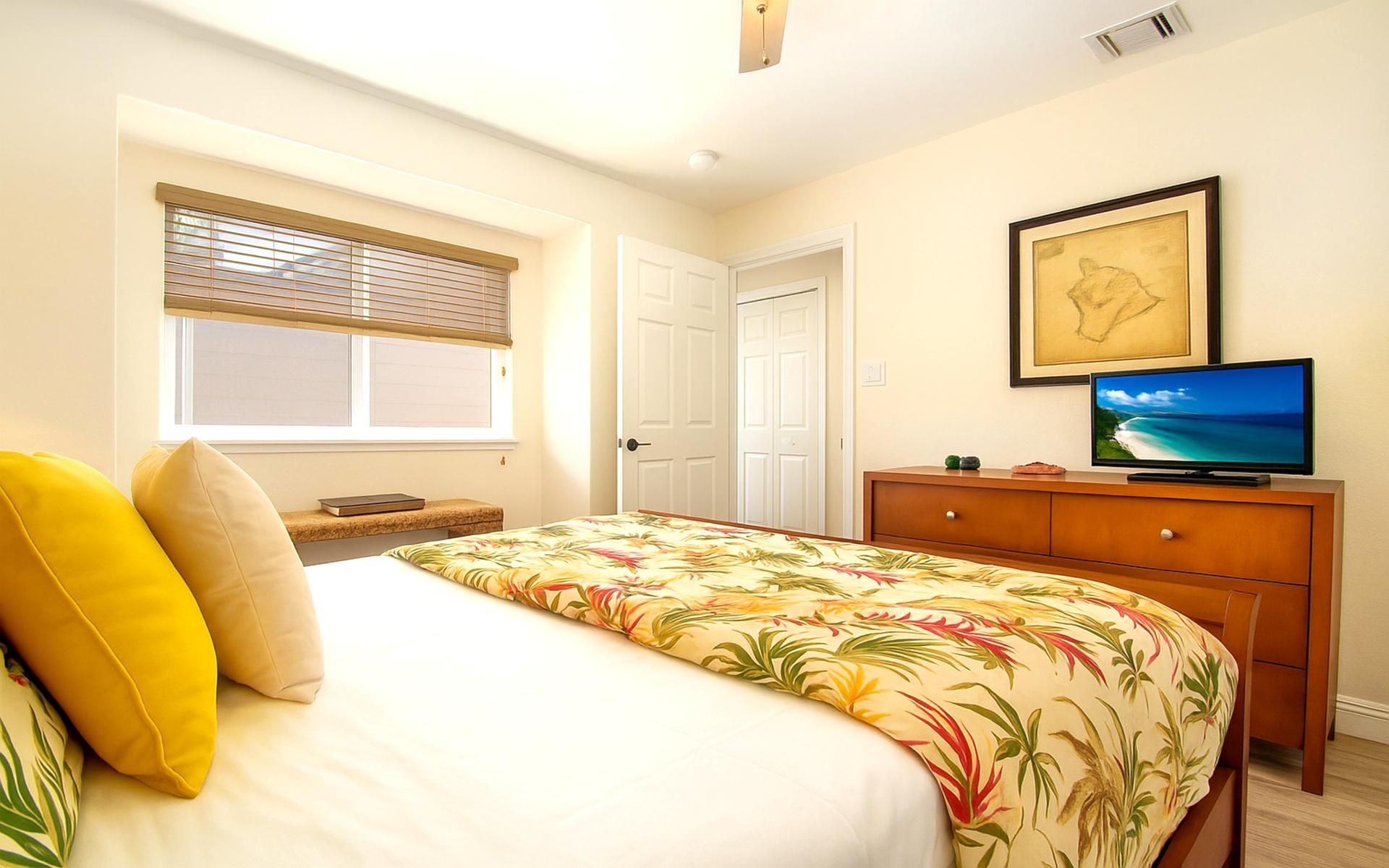 A bedroom with a bed, a television, a dresser, and a window with blinds.