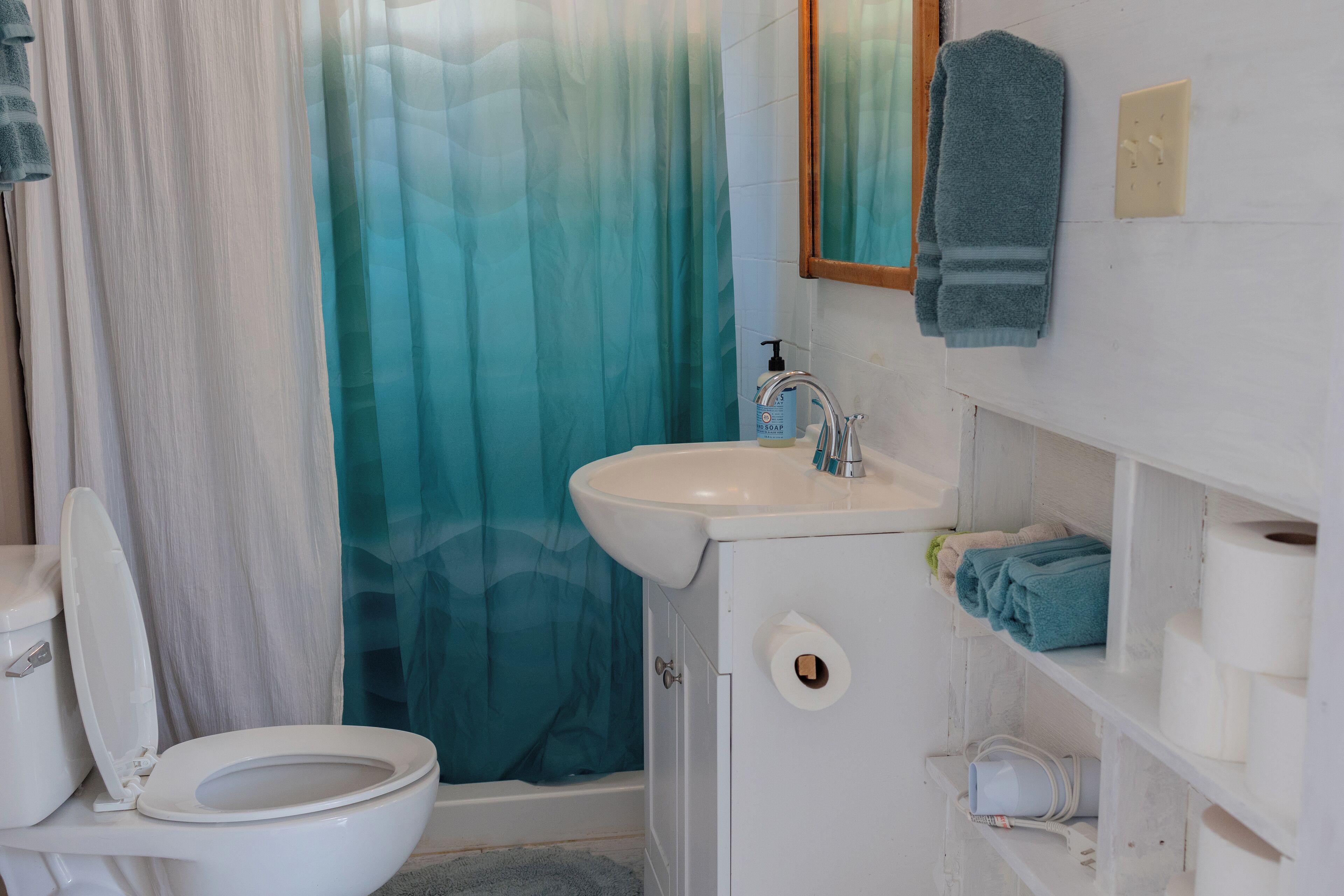 A bathroom with a toilet, sink, and shower curtain.