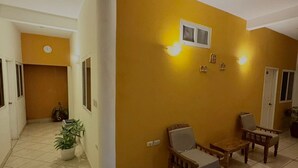 Un hall d’entrée spacieux avec un mur jaune, une horloge et un luminaire fixé au mur.