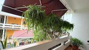 Un balcon doté d’un plancher en bois, d’une balustrade blanche et de plantes suspendues.