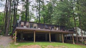 A two-story cabin with a balcony, surrounded by tall trees. - Charming 3-bedroom cabin with WiFi, AC in tranquil Waterville (Waterville)