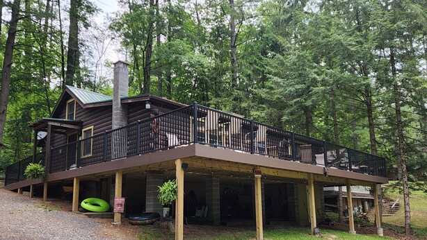 A cabin with a covered deck and a chimney, surrounded by trees. - Charming 3-bedroom cabin with WiFi, AC in tranquil Waterville (Waterville)