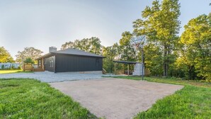 A residential property with a covered patio, a basketball hoop, and a house with a dark exterior. - Spacious 5-bedroom just 1 minute from Bennett Spring State Park! (Lebanon)