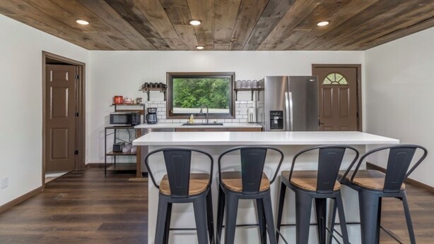 A modern kitchen with a large island, bar stools, and a view of greenery through a window. - Spacious 5-bedroom just 1 minute from Bennett Spring State Park! (Lebanon)