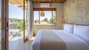 A bedroom with a large bed, a view of the outdoors, and a ceiling fan.