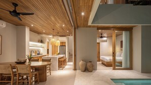 A modern interior with a dining area, kitchen, and a bedroom with a sliding door leading to a balcony.