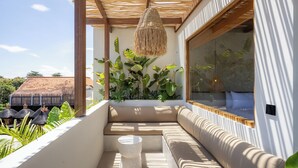 A modern outdoor seating area with a woven ceiling light, a cushioned bench, and a round table.