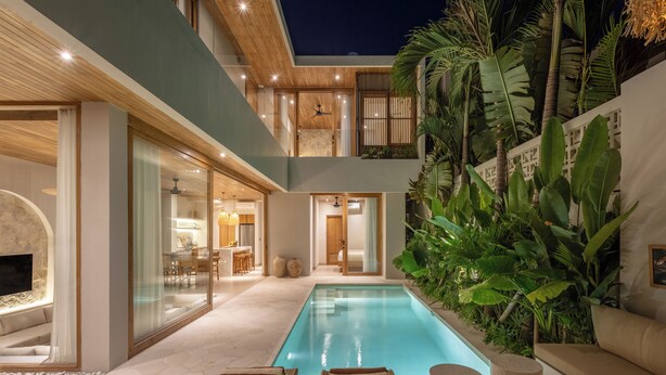 A modern house with a swimming pool, outdoor seating, and lush greenery.