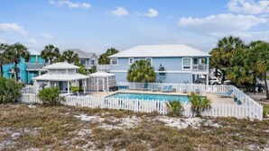 A beachfront property with a pool, white picket fence, and multiple buildings with balconies.