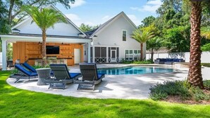 Una casa moderna con piscina, zona de estar exterior y porche cubierto.