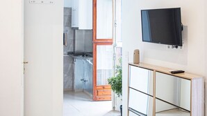 A modern kitchen with a large window, a TV mounted on the wall, and a painting above the door. - APARTMENTS THE MUSHROOMS. HISTORICAL CENTER (Sevilla)
