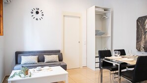 A modern living room with a grey sofa, white coffee table, and a dining area with a table set for four. - APARTMENTS THE MUSHROOMS. HISTORICAL CENTER (Sevilla)