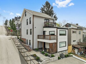 Una casa moderna de dos pisos con balcón, garaje y entrada para vehículos.