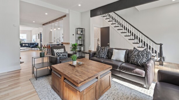 A modern living room with a wooden coffee table, leather sofa, and a staircase. - 3BR Stylish Retreat, Minutes from Downtown Pittsburgh, Free 3-Car Parking (Pittsburgh)