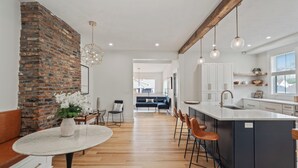 A modern kitchen with a central island, wooden flooring, and pendant lighting. - 3BR Stylish Retreat, Minutes from Downtown Pittsburgh, Free 3-Car Parking (Pittsburgh)