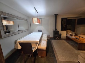 Uma sala de estar moderna com uma mesa de jantar comprida, lareira e sofá.