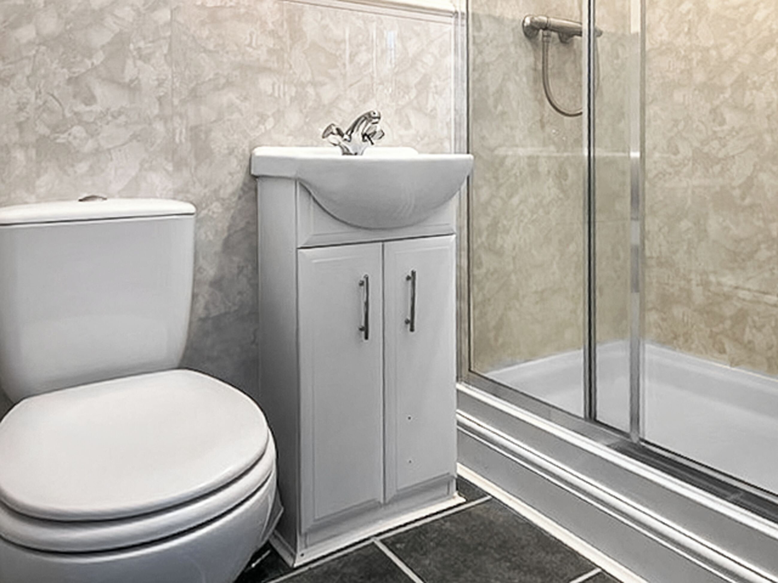 Un baño con inodoro, lavamanos y ducha.