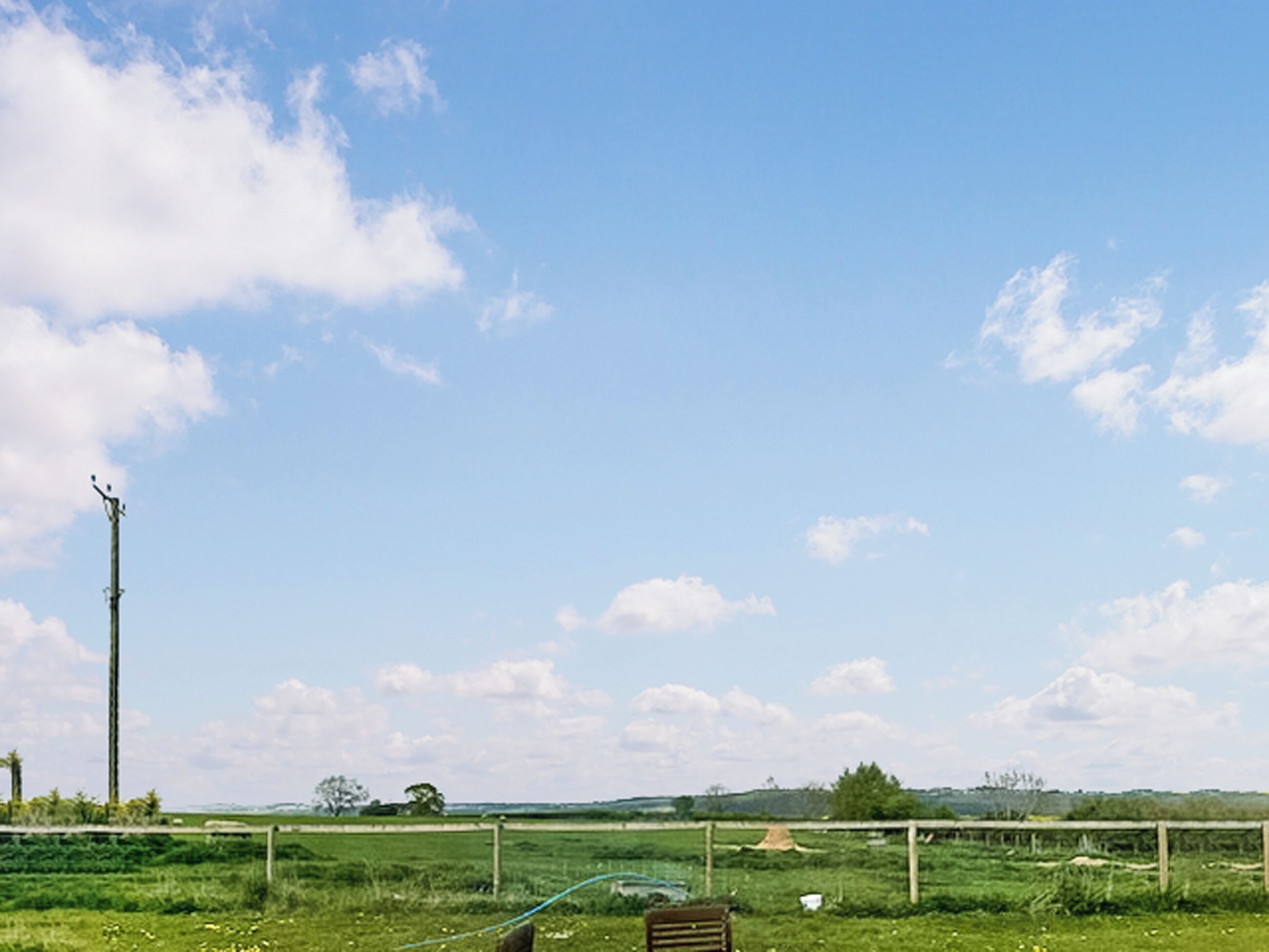 A rural landscape with a clear sky, a utility pole, and a fence.