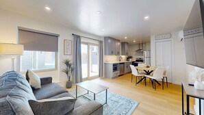 Un appartement moderne comprenant un salon, un coin repas, une cuisine et un balcon.
