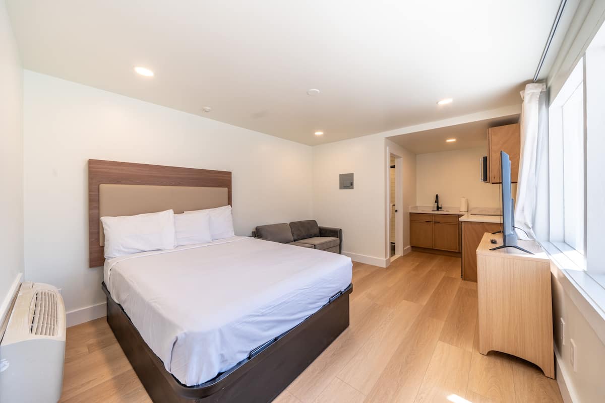 A bedroom with a bed, a desk, a chair, and a TV.