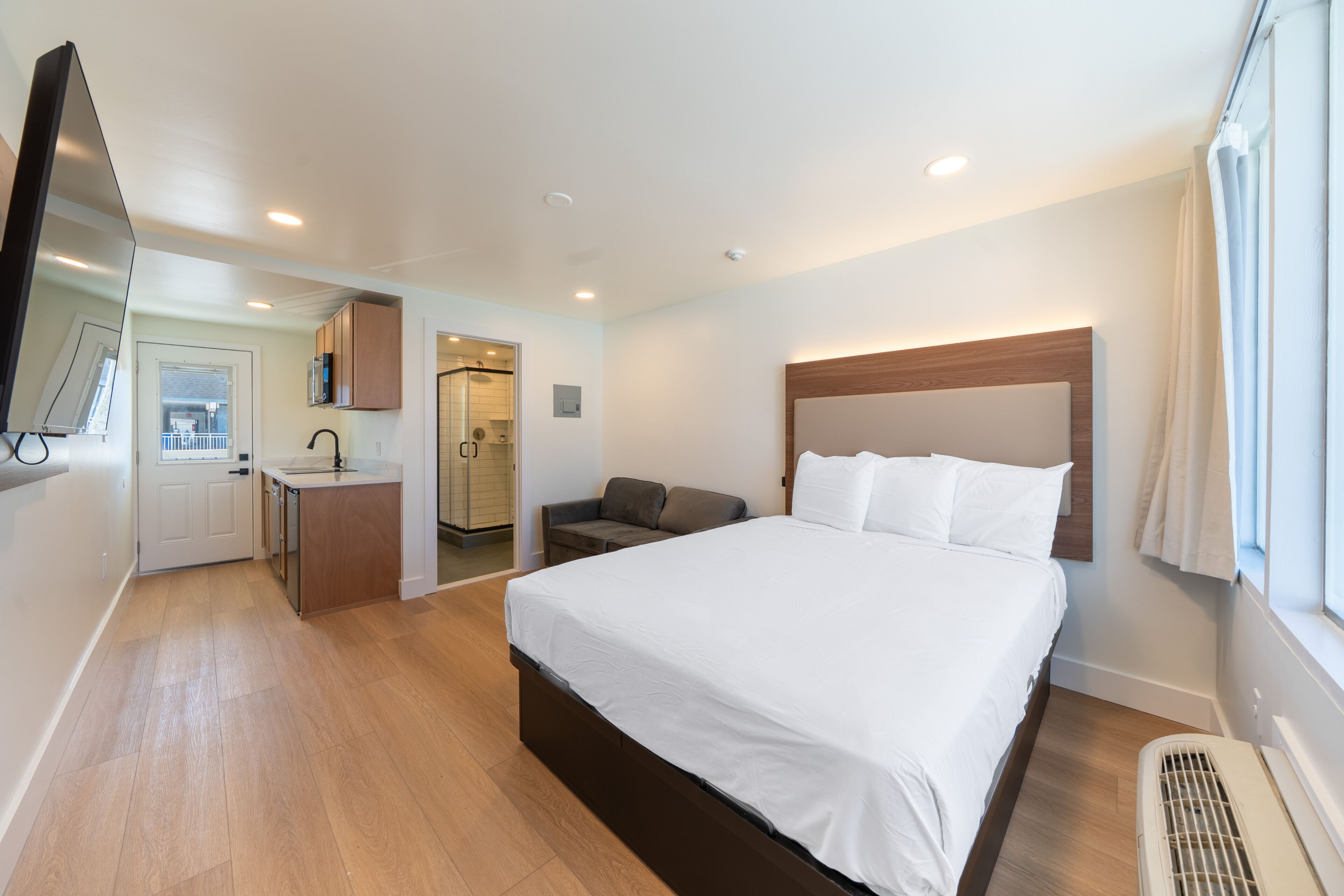 Une chambre d’hôtel avec un lit, un bureau, une chaise, une télévision et une fenêtre.