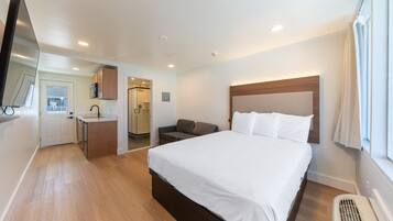 A hotel room with a bed, a desk, a chair, a TV, and a window.