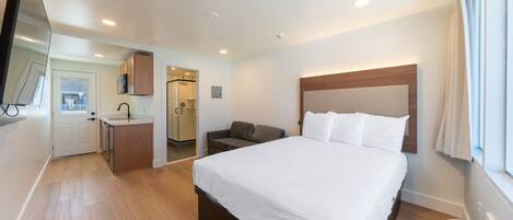 Une chambre d’hôtel avec un lit, un bureau, une chaise, une télévision et une fenêtre.
