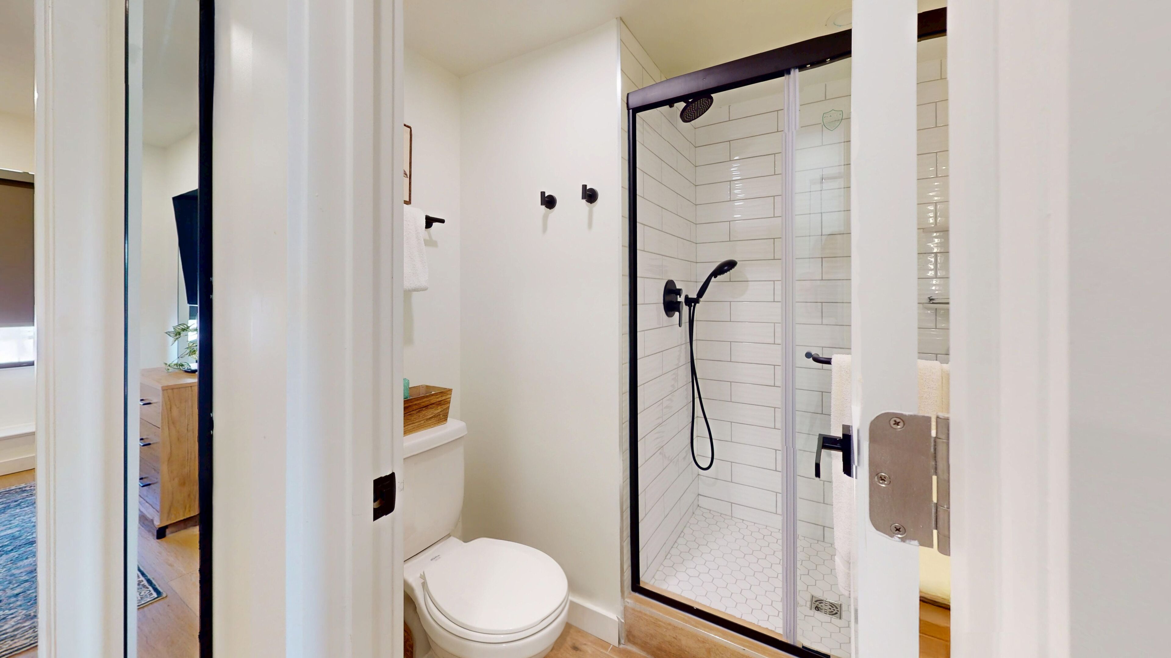 Un baño moderno con inodoro, ducha con puerta de vidrio y toallero.