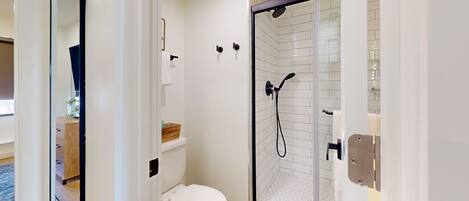 A modern bathroom with a toilet, a shower with a glass door, and a towel rack.