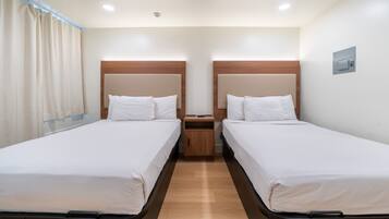 Ein Doppelzimmer mit zwei Betten, Holz-Kopfteilen, einem Nachttisch und einer Deckenleuchte.