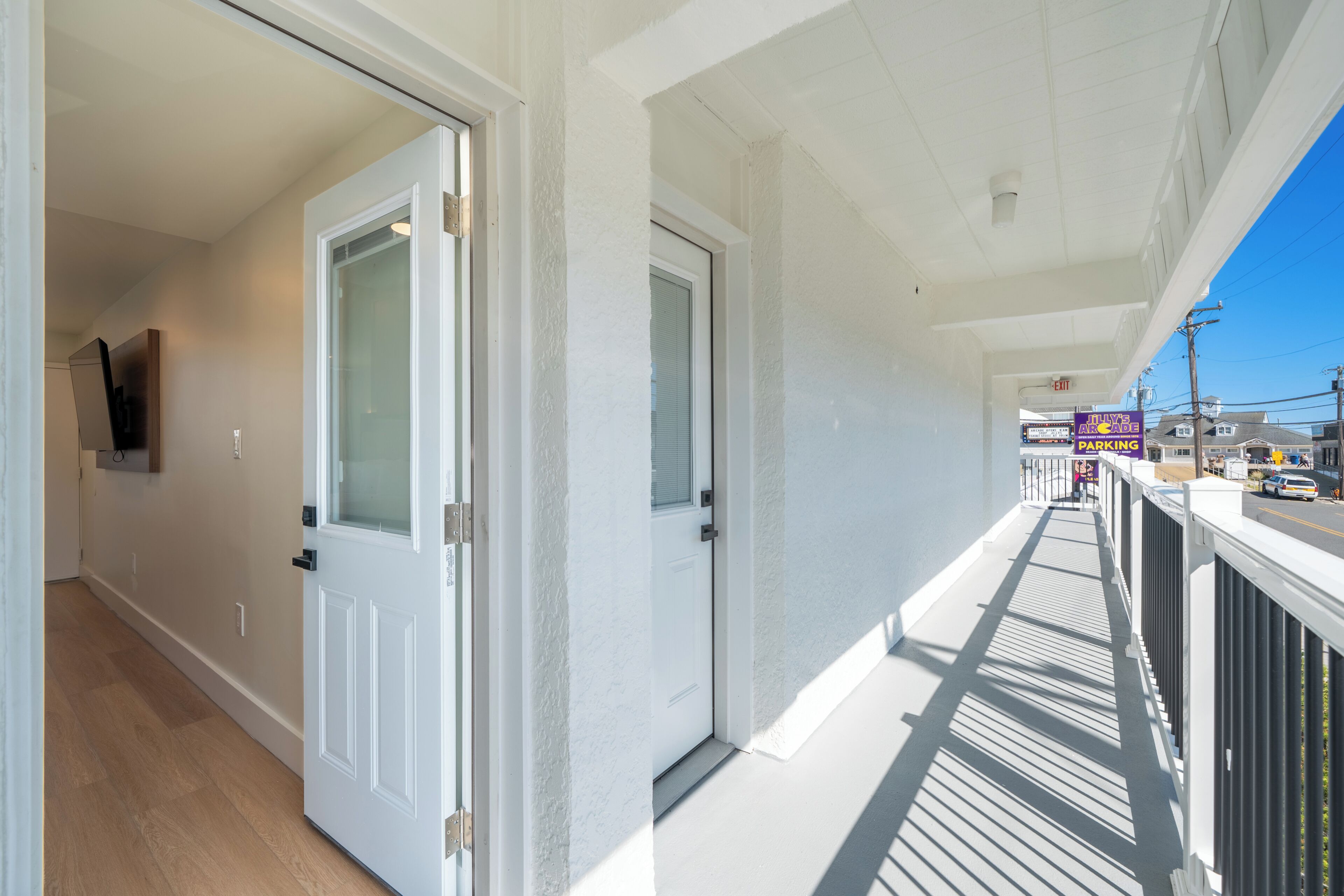Un couloir avec des portes blanches, un balcon avec une balustrade et une vue dégagée sur la rue.
