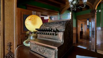 A vintage typewriter with ornate designs, a lamp with floral patterns, and a chandelier in a room with wooden paneling and green walls.