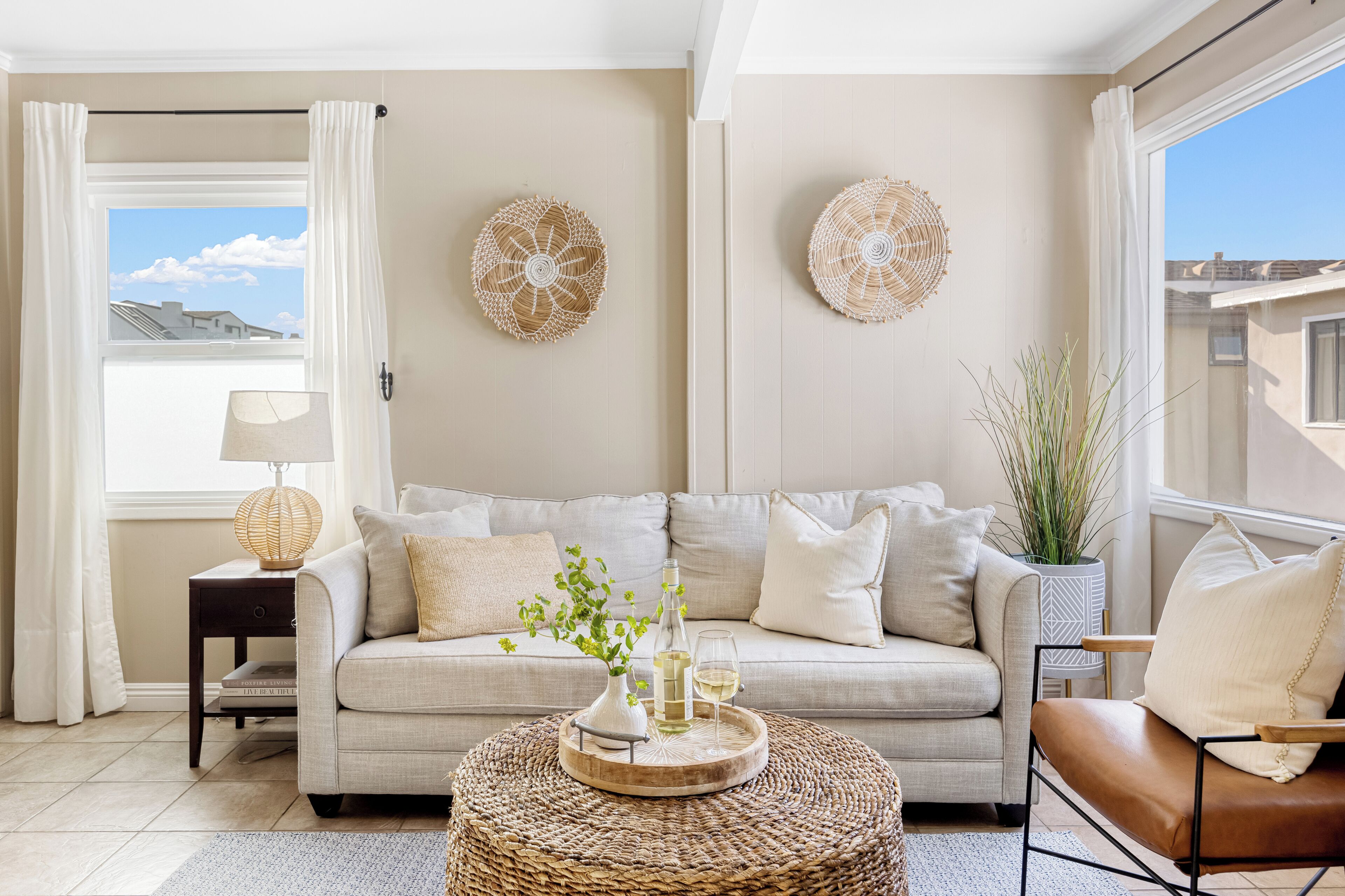 A living room with a beige sofa, a coffee table with decorative items, a lamp, and two wall art pieces.