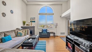 A modern living room with a fireplace, a large window, a television, and a dining area.