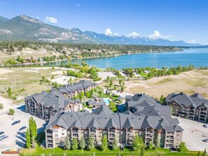 Un resort con diversi edifici, una piscina e vista su un lago e le montagne.