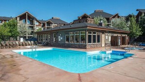 A pool area with a building that has large windows and a stone facade.